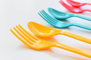Beyaz arka planda izole edilmiş renkli kaşık ve çatal, piknik için plastik çatal