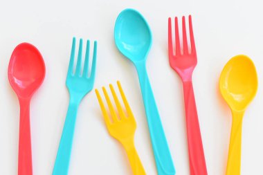 Beyaz arka planda izole edilmiş renkli kaşık ve çatal, piknik için plastik çatal