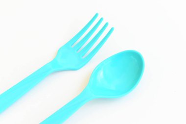 Beyaz arkaplanda mavi kaşık ve çatal, piknik için plastik çatal.