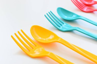 Beyaz arka planda izole edilmiş renkli kaşık ve çatal, piknik için plastik çatal