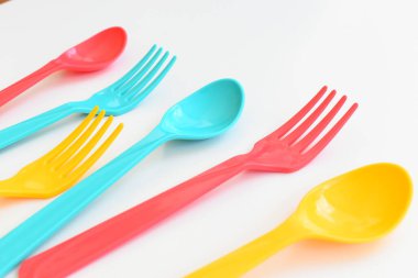 Beyaz arka planda izole edilmiş renkli kaşık ve çatal, piknik için plastik çatal
