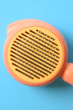 Mavi arka planda pastel turuncu tarak, evcil hayvan için saç fırçası