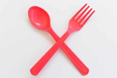 Kırmızı kaşık ve çatal beyaz arka planda izole edilmiş, plastik çatal bıçak takımı piknik için.