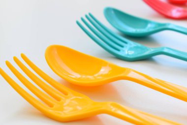 Beyaz arka planda izole edilmiş renkli kaşık ve çatal, piknik için plastik çatal
