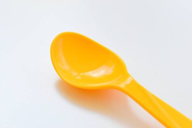 Beyaz arka planda izole edilmiş sarı kaşık, piknik için plastik çatal bıçak.