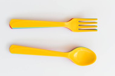 Beyaz arka planda izole edilmiş sarı kaşık ve çatal, piknik için plastik çatal bıçak.