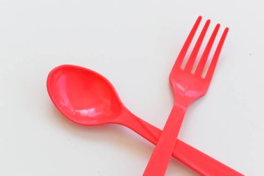 Kırmızı kaşık ve çatal beyaz arka planda izole edilmiş, plastik çatal bıçak takımı piknik için.