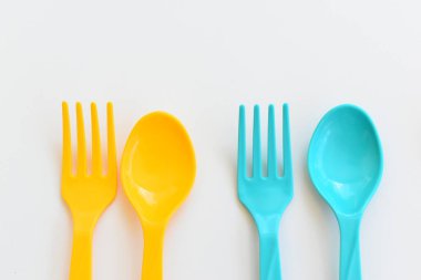 Beyaz arka planda izole edilmiş renkli kaşık ve çatal, piknik için plastik çatal