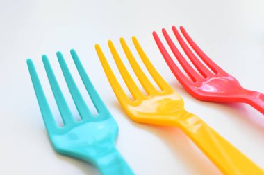 Beyaz arkaplanda renkli çatal, piknik için plastik çatal.