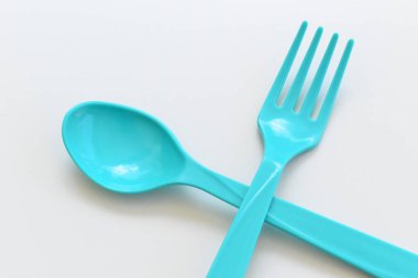 Beyaz arkaplanda mavi kaşık ve çatal, piknik için plastik çatal.
