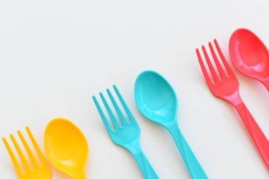 Beyaz arka planda izole edilmiş renkli kaşık ve çatal, piknik için plastik çatal