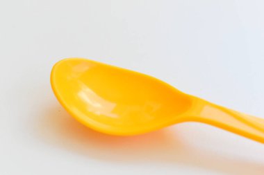 Beyaz arka planda izole edilmiş sarı kaşık, piknik için plastik çatal bıçak.