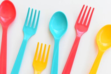 Beyaz arka planda izole edilmiş renkli kaşık ve çatal, piknik için plastik çatal