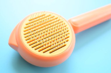Mavi arka planda pastel turuncu tarak, evcil hayvan için saç fırçası