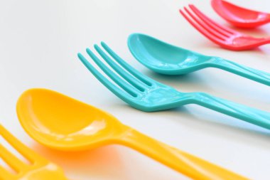 Beyaz arka planda izole edilmiş renkli kaşık ve çatal, piknik için plastik çatal