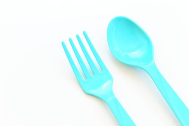 Beyaz arkaplanda mavi kaşık ve çatal, piknik için plastik çatal.
