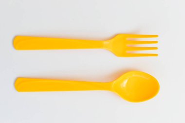 Beyaz arka planda izole edilmiş sarı kaşık ve çatal, piknik için plastik çatal bıçak.
