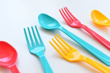 Beyaz arka planda izole edilmiş renkli kaşık ve çatal, piknik için plastik çatal