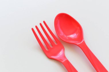 Kırmızı kaşık ve çatal beyaz arka planda izole edilmiş, plastik çatal bıçak takımı piknik için.