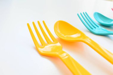 Beyaz arka planda izole edilmiş renkli kaşık ve çatal, piknik için plastik çatal