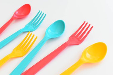 Beyaz arka planda izole edilmiş renkli kaşık ve çatal, piknik için plastik çatal