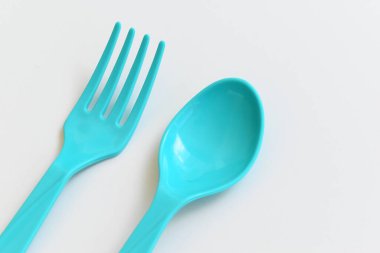 Beyaz arkaplanda mavi kaşık ve çatal, piknik için plastik çatal.
