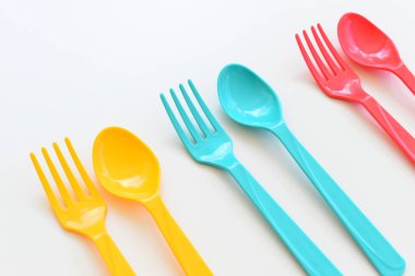 Beyaz arka planda izole edilmiş renkli kaşık ve çatal, piknik için plastik çatal