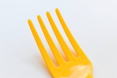 Beyaz arka planda sarı çatal, piknik için plastik çatal.