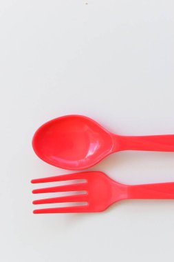 Kırmızı kaşık ve çatal beyaz arka planda izole edilmiş, plastik çatal bıçak takımı piknik için.