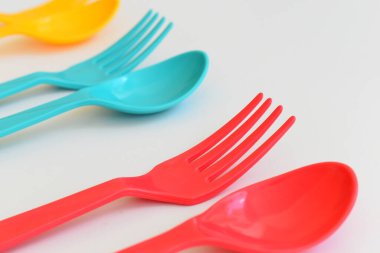 Beyaz arka planda izole edilmiş renkli kaşık ve çatal, piknik için plastik çatal