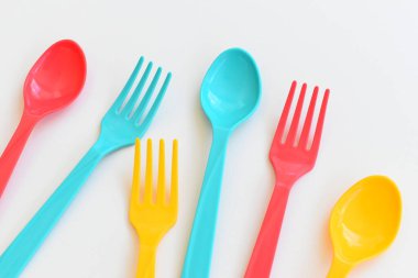 Beyaz arka planda izole edilmiş renkli kaşık ve çatal, piknik için plastik çatal
