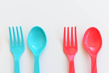 Beyaz arka planda izole edilmiş renkli kaşık ve çatal, piknik için plastik çatal