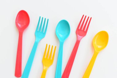 Beyaz arka planda izole edilmiş renkli kaşık ve çatal, piknik için plastik çatal