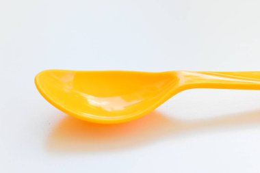 Beyaz arka planda izole edilmiş sarı kaşık, piknik için plastik çatal bıçak.