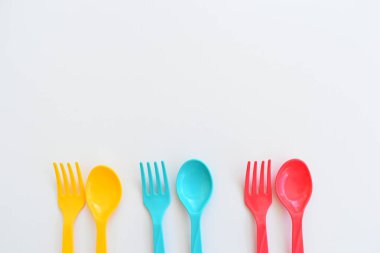 Beyaz arka planda izole edilmiş renkli kaşık ve çatal, piknik için plastik çatal
