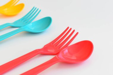 Beyaz arka planda izole edilmiş renkli kaşık ve çatal, piknik için plastik çatal
