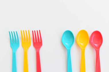 Beyaz arka planda izole edilmiş renkli kaşık ve çatal, piknik için plastik çatal
