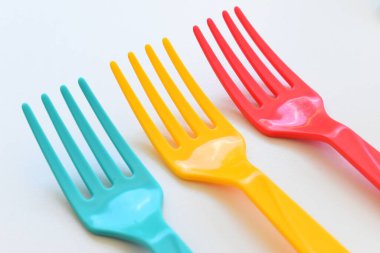 Beyaz arkaplanda renkli çatal, piknik için plastik çatal.