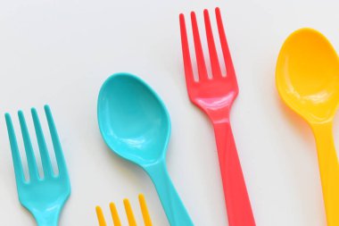 Beyaz arka planda izole edilmiş renkli kaşık ve çatal, piknik için plastik çatal