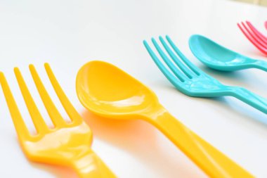 Beyaz arka planda izole edilmiş renkli kaşık ve çatal, piknik için plastik çatal