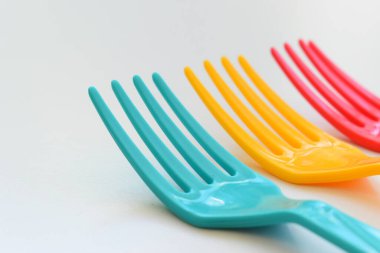Beyaz arkaplanda renkli çatal, piknik için plastik çatal.