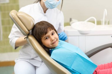 Doktor ofisindeki kız dişçi koltuğunda oturuyor.