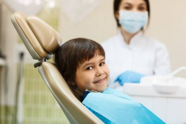 Gülümseyen küçük kız dişçi koltuğunda