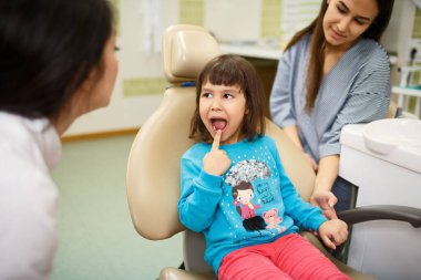 Annem doktoruna dişlerini gösterirken küçük kızının elini tutuyor.