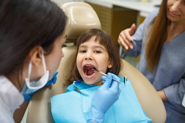 Dişlerini çocuk doktoruna gösteren küçük bir kız.