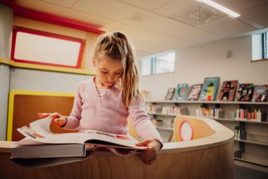 Kütüphanede kitap okuyan küçük bir kız. Yüksek kalite fotoğraf. Eğlence konseptini öğreniyorum. Aşk okuma kavramı. 