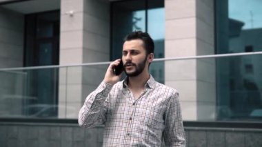 Yakışıklı beyaz stil çekici bir adam telefonda konuşuyor ve yakından gülümsüyor.