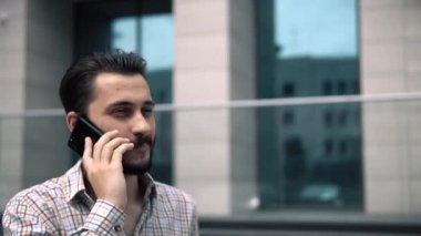 Yakışıklı beyaz stil çekici bir adam telefonda konuşuyor ve yakından gülümsüyor.