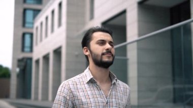 Çekici beyaz adam modern bir şehir binası boyunca ağır çekimde ilerliyor.