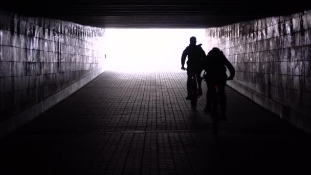 两个骑自行车的人正穿过一条地下通道而去 — 图库视频影像